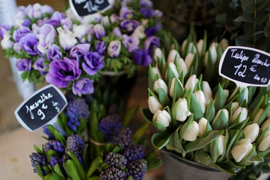 A close-up view of fresh flower bouquets displayed at Chelsea florist, featuring a collection of purple and white flowers. On the left, there is a bouquet of purple tulips with creamy white edges, arr
